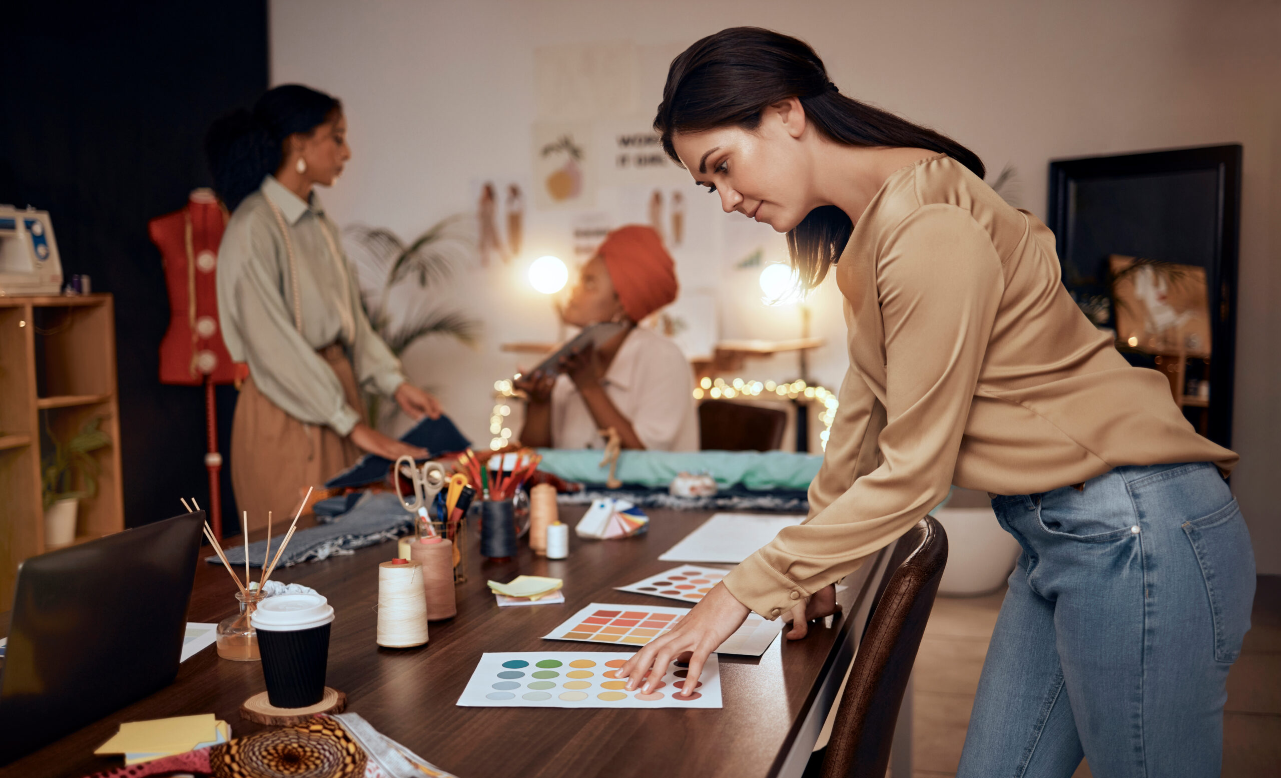 Small business owner looking at swatches while colleagues are in the background discussing business